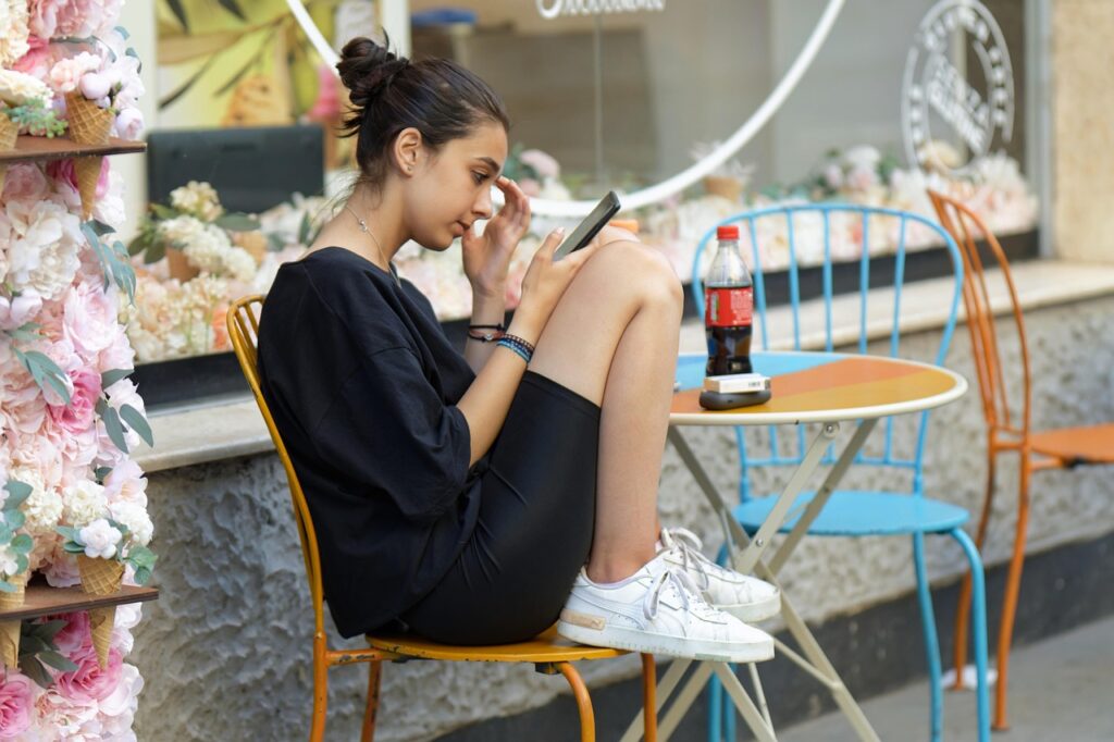 girl, sitting, casual, crouched, outdoors, looking, smartphone, cafe, woman-7369791.jpg